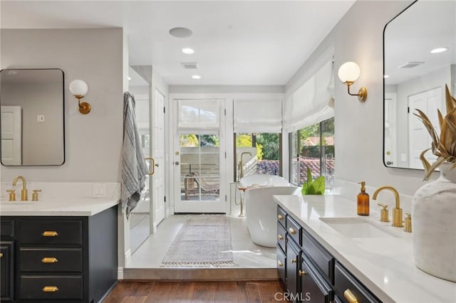 bathroom featuring wood finished floors, two vanities, a sink, and visible vents