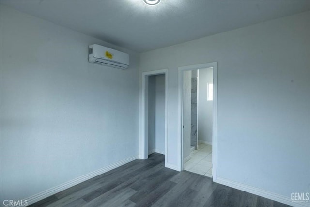 unfurnished bedroom with a wall mounted air conditioner and dark hardwood / wood-style floors