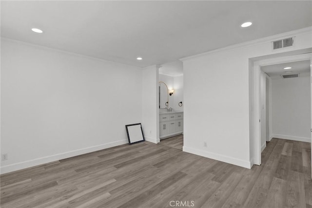 spare room with light hardwood / wood-style floors and crown molding