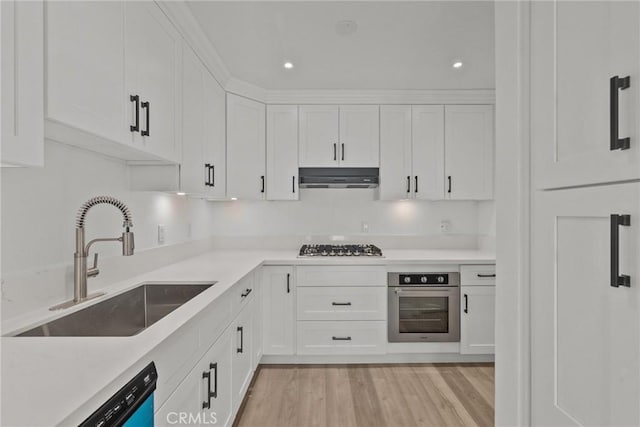 kitchen featuring appliances with stainless steel finishes, sink, white cabinetry, and light wood-type flooring