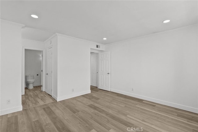 spare room featuring light wood-type flooring and crown molding