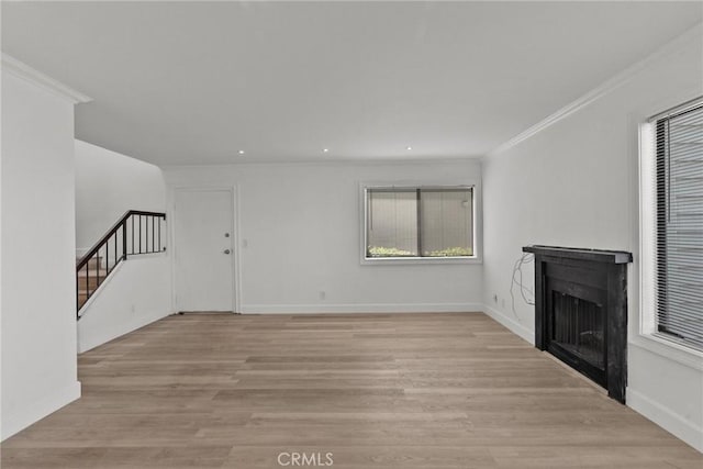 unfurnished living room featuring light hardwood / wood-style floors, plenty of natural light, and crown molding