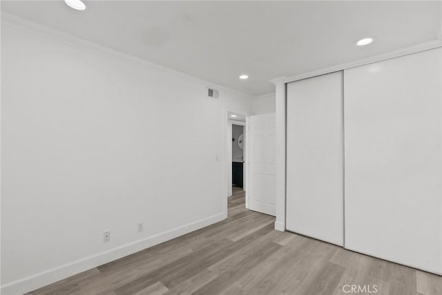 unfurnished bedroom with ornamental molding, light hardwood / wood-style floors, and a closet