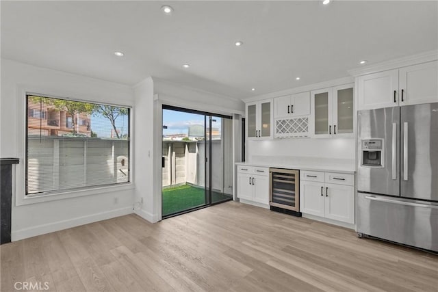 kitchen with white cabinets, beverage cooler, stainless steel fridge, and light hardwood / wood-style floors