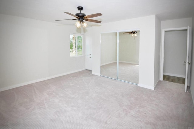 unfurnished bedroom with a closet, light colored carpet, and ceiling fan