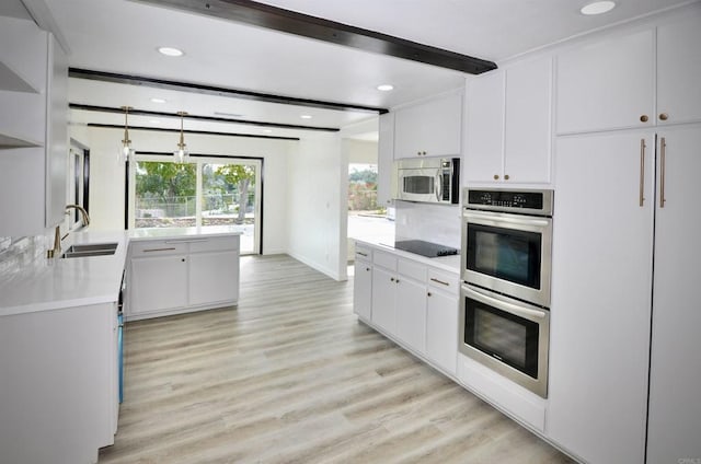 kitchen featuring sink, light wood-type flooring, white cabinetry, stainless steel appliances, and beam ceiling