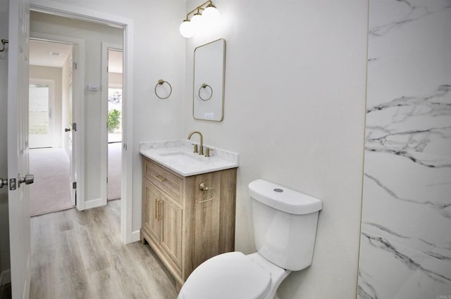 bathroom featuring toilet, hardwood / wood-style flooring, and vanity