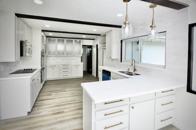 kitchen featuring white cabinetry, kitchen peninsula, stainless steel appliances, sink, and pendant lighting