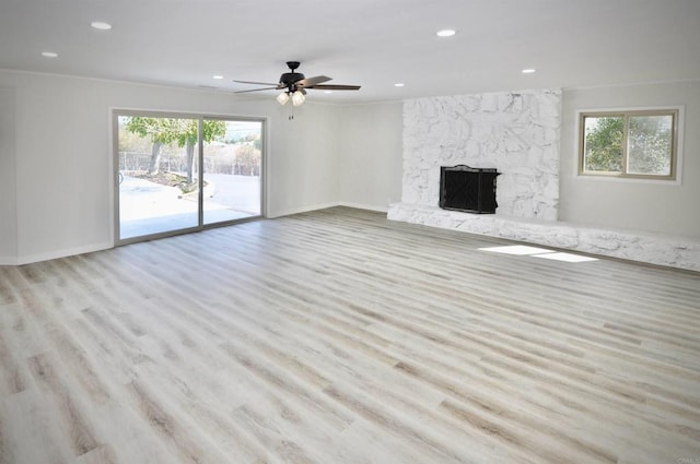 unfurnished living room with light wood-type flooring, ceiling fan, and a fireplace