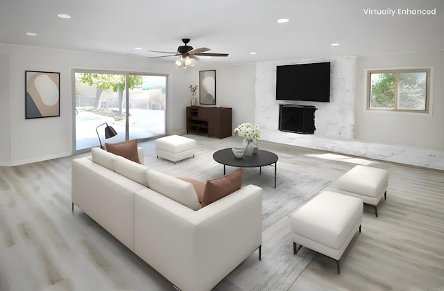 living room with a fireplace, ceiling fan, light hardwood / wood-style floors, and plenty of natural light