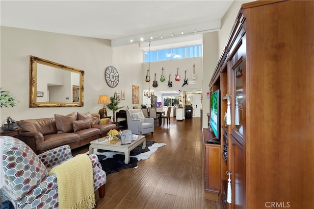 living room featuring a high ceiling, rail lighting, and dark hardwood / wood-style flooring