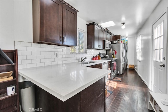 kitchen featuring kitchen peninsula, stainless steel appliances, tasteful backsplash, and sink