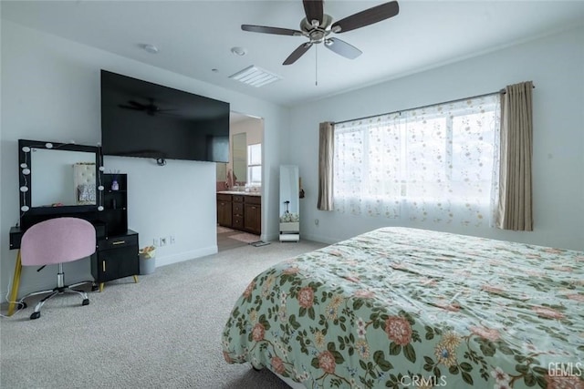 bedroom featuring light colored carpet, ceiling fan, and ensuite bath