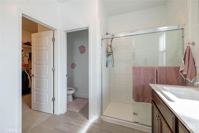 bathroom featuring toilet, vanity, and walk in shower