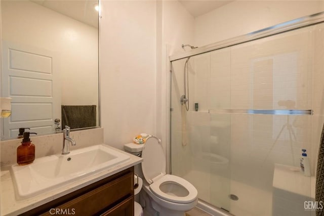 bathroom featuring an enclosed shower, vanity, and toilet