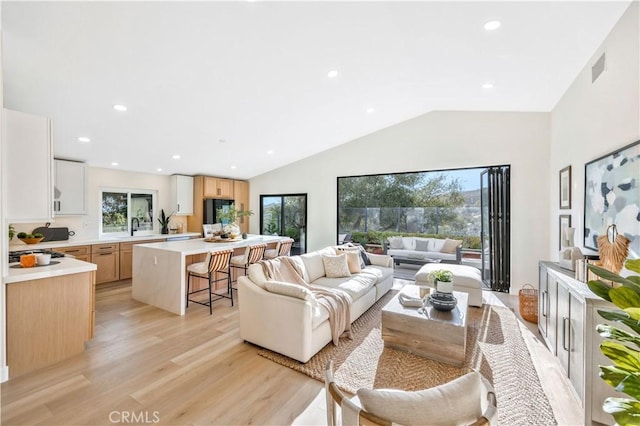 living room with light wood-type flooring, recessed lighting, visible vents, and lofted ceiling