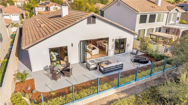 back of property with an outdoor living space with a fire pit, fence, a chimney, and stucco siding