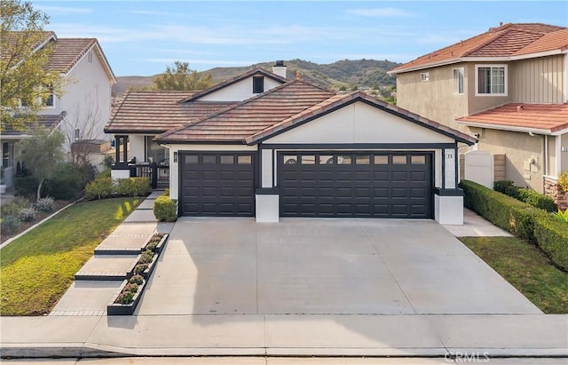 view of front of house featuring driveway, a garage, a mountain view, and a tiled roof