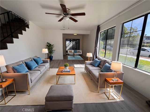 living area with stairs, plenty of natural light, wood finished floors, and baseboards