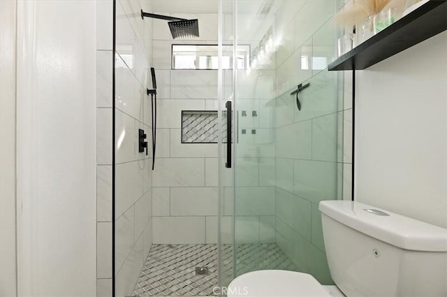 bathroom with a shower with shower door and toilet