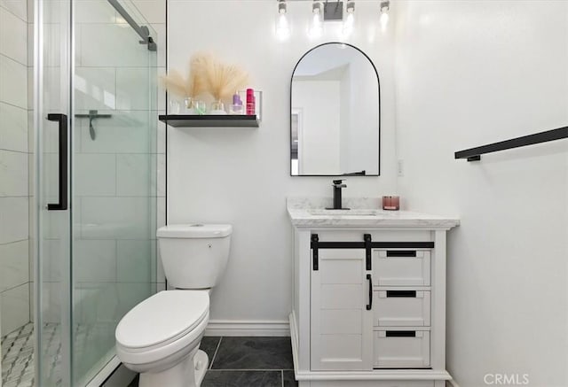 bathroom with toilet, vanity, and a shower with shower door