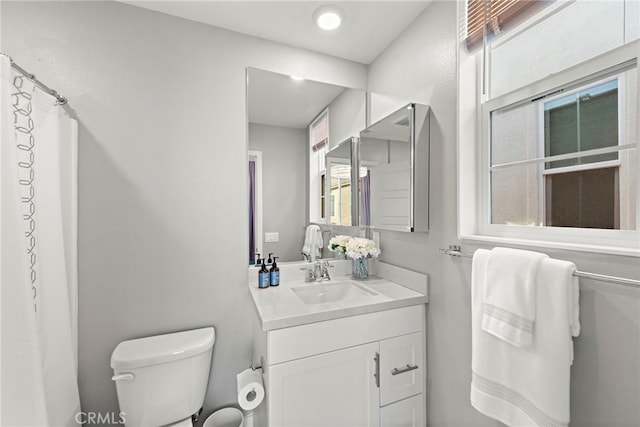 bathroom with toilet, vanity, and walk in shower