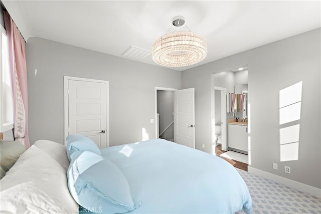 carpeted bedroom featuring a notable chandelier and ensuite bath