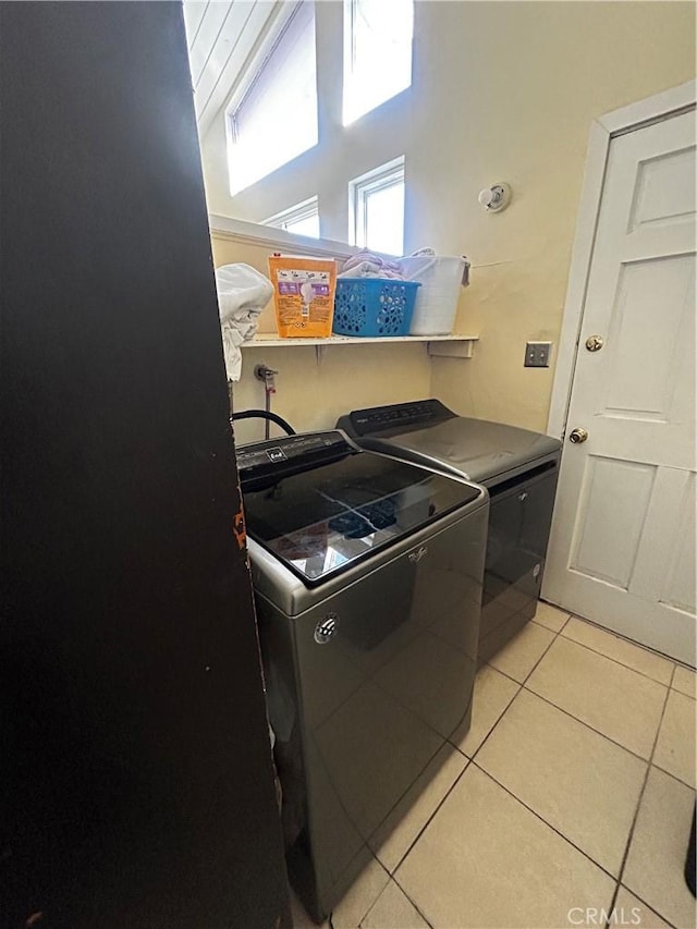 clothes washing area featuring light tile patterned floors, laundry area, and washing machine and dryer