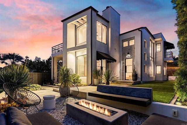 rear view of house with fence, a patio, a fire pit, and stucco siding