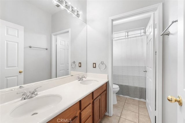 bathroom with toilet, tile patterned floors, double vanity, and a sink