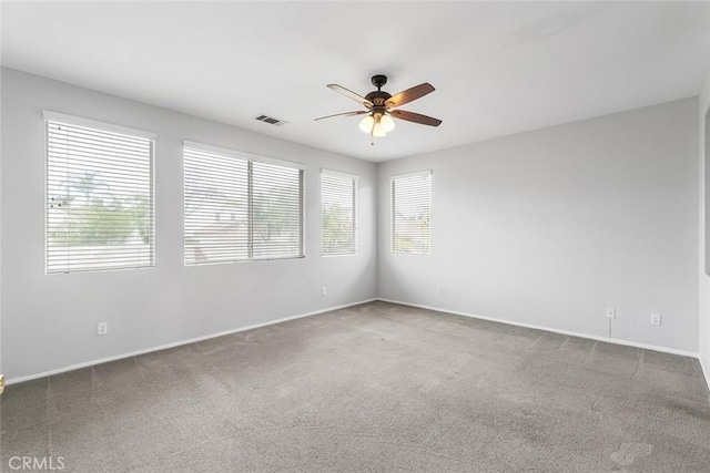 empty room with baseboards, a ceiling fan, visible vents, and carpet floors