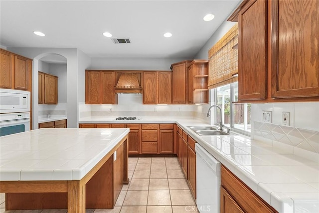 kitchen featuring white appliances, premium range hood, open shelves, visible vents, and a sink