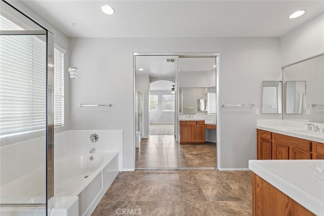 full bath with a bath, vanity, baseboards, and a stall shower