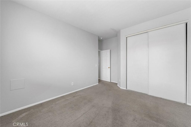 unfurnished bedroom with carpet, a closet, and baseboards