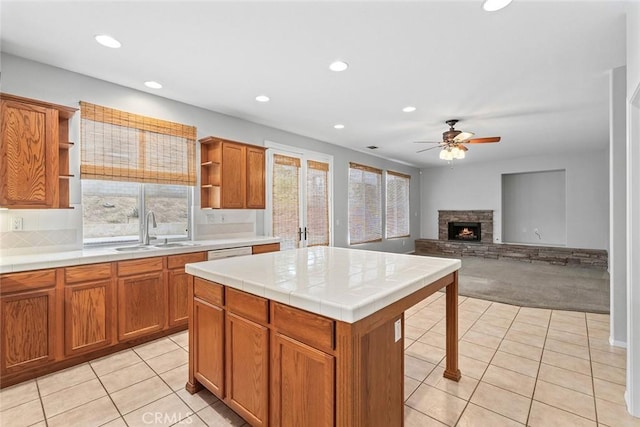 kitchen with tile countertops, light colored carpet, a ceiling fan, open shelves, and a sink