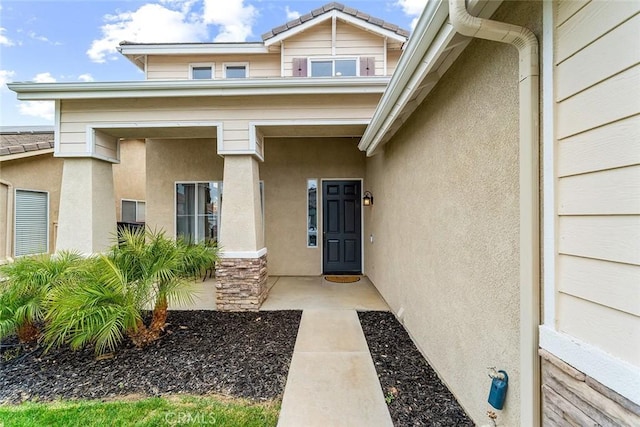entrance to property featuring stucco siding and stone siding