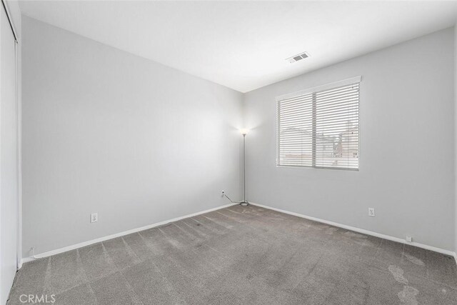 unfurnished room with visible vents, baseboards, and carpet