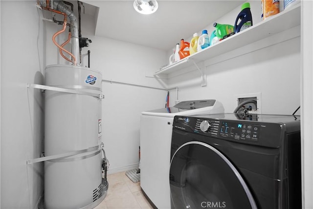 laundry area featuring light tile patterned floors, water heater, and separate washer and dryer