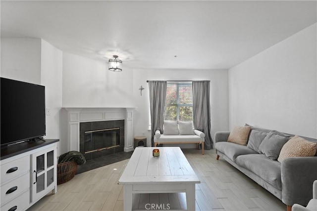 living room with a tile fireplace and light wood-type flooring