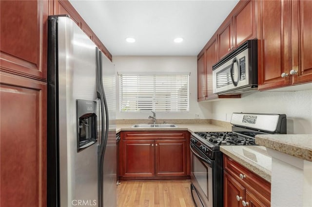 kitchen with light hardwood / wood-style flooring, stainless steel appliances, light stone counters, and sink