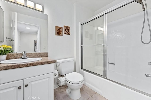 full bathroom with combined bath / shower with glass door, vanity, toilet, and tile patterned floors