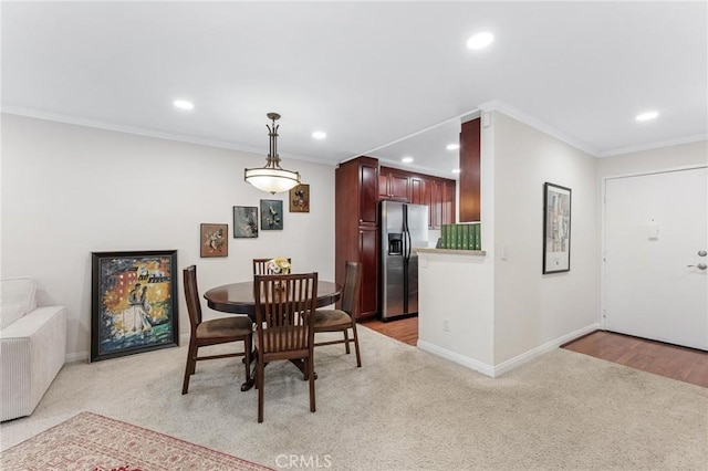 dining room with crown molding and light colored carpet