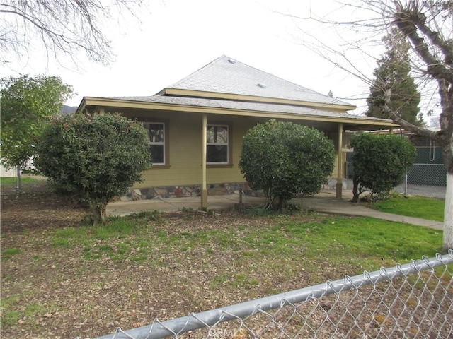 view of home's exterior with roof with shingles, a lawn, and fence