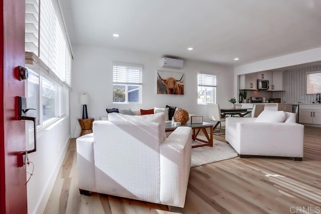 living room featuring light hardwood / wood-style flooring, sink, and an AC wall unit