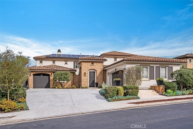 mediterranean / spanish home with a garage, roof mounted solar panels, and concrete driveway