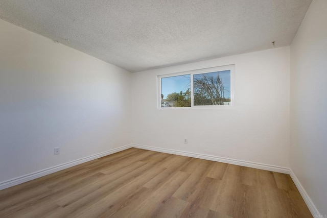 unfurnished room with light hardwood / wood-style flooring and a textured ceiling