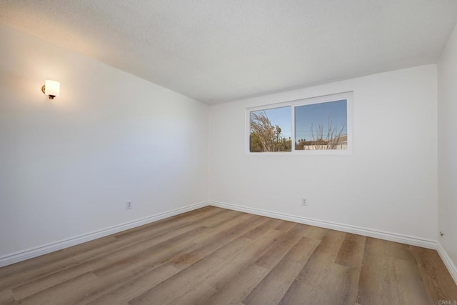 empty room with light hardwood / wood-style flooring and a textured ceiling