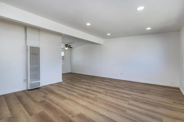 spare room featuring light wood-type flooring, ceiling fan, and beam ceiling