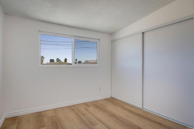 unfurnished bedroom featuring light hardwood / wood-style flooring, a textured ceiling, and a closet