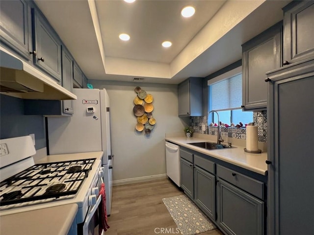 2230 S Palm Canyon Dr Unit 7, Palm Springs, CA 92264 - kitchen featuring white appliances, a tray ceiling, decorative backsplash, light countertops, and light wood-style flooring